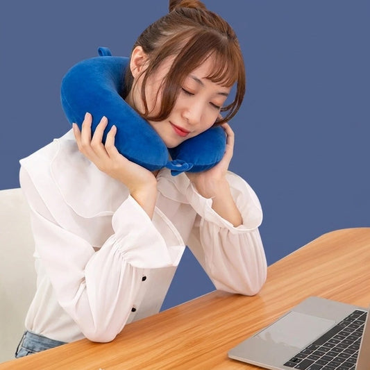 Femme faisant une sieste au bureau, la tête calée par un coussin de voyage en U bleu