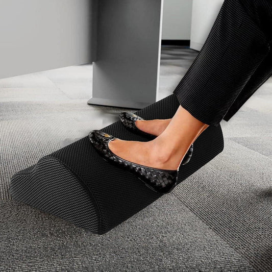 Pieds chaussés posés sur un coussin noir en demi-cylindre sous un bureau