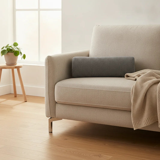 Coussin cylindrique gris posé sur un canapé