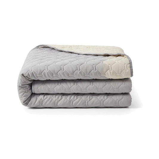 Protection de canapé pour chien gris clair, matelassée, pliée, revers crème visible, sur fond blanc