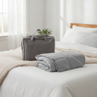 Couverture lestée Sweikett 7 kg gris avec son sac de transport sur un lit