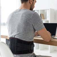 Un homme travaille à son bureau, la ceinture chauffante portée sur le bas du dos