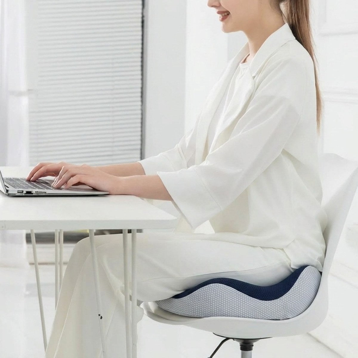 Femme en télétravail assise sur une chaise équipée du coussin ergonomique ErgoSeat
