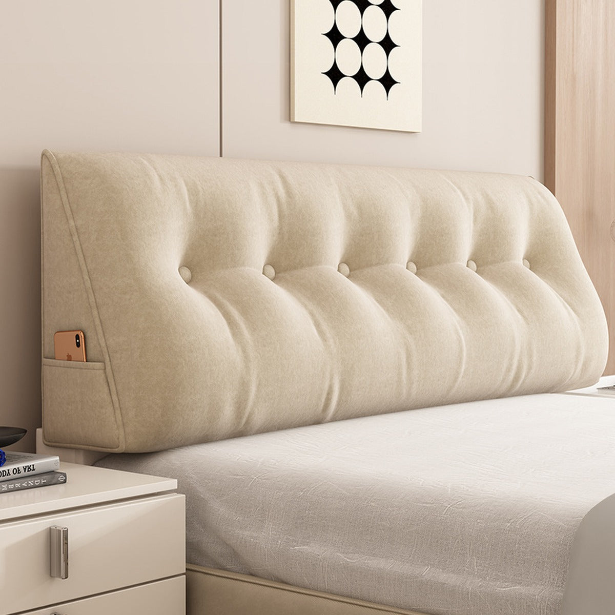 Le coussin de relax beige posé contre la tête de lit, dans une chambre claire