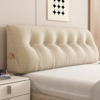 Le coussin de relax beige posé contre la tête de lit, dans une chambre claire