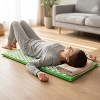 Femme allongée sur le dos sur le tapis d'acupression, la tête posée sur une serviette pliée