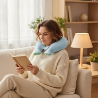 Mise en situation : femme lisant sur un canapé, la bouillotte en U bleu ciel autour de la nuque