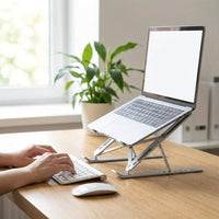 Ordinateur portable surélevé sur le support, clavier et souris séparés sur un bureau en bois