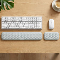 Mise en situation : repose-poignets gris devant le clavier et la souris, sur un bureau en chêne