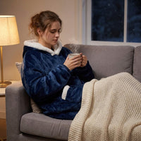 Mise en situation : femme lovée dans le canapé en sweat plaid bleu, une tasse à la main