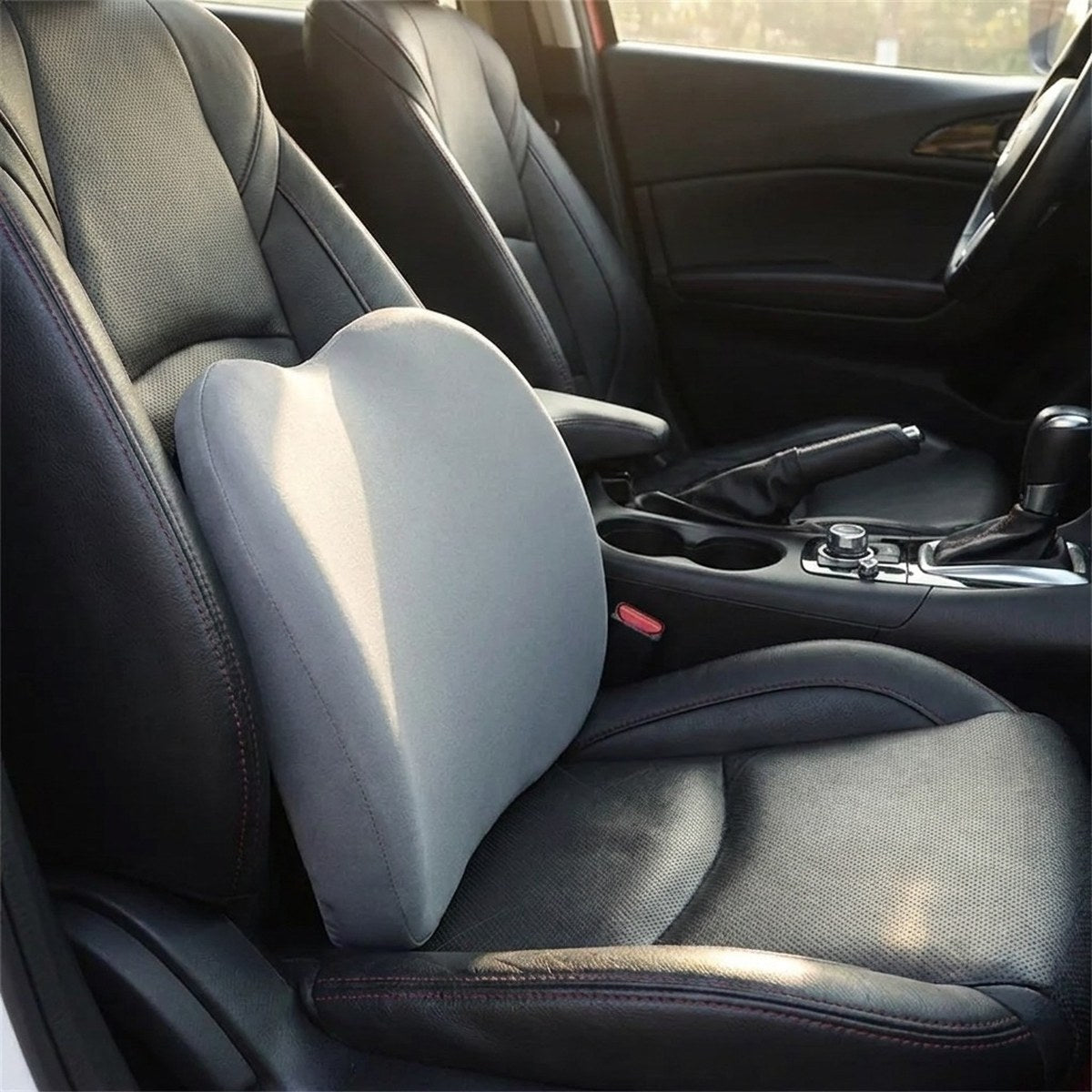 Coussin gris utilisé comme appui pour le bas du dos contre le dossier d’un siège de voiture