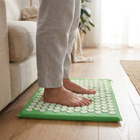 Pieds nus posés debout sur le tapis d'acupression, près d'un canapé