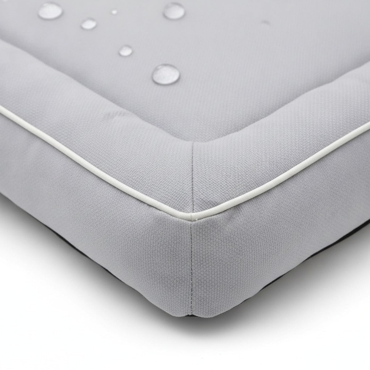 Détail : tissu Oxford serré, gouttes d'eau qui perlent, bord rembourré et passepoil blanc