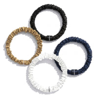 Assortiment Classiques : chouchous en soie noir, or, marine et blanc, sur fond blanc