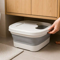 Le Bain de Pieds Pliable AquaRetreat™ rangé discrètement sous un meuble de salle de bain, illustrant sa facilité de rangement et son gain de place.