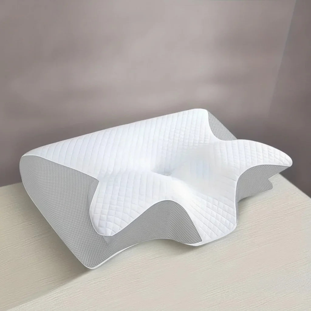 Oreiller cervical CerviCore gris clair posé sur un lit, vue de trois quarts