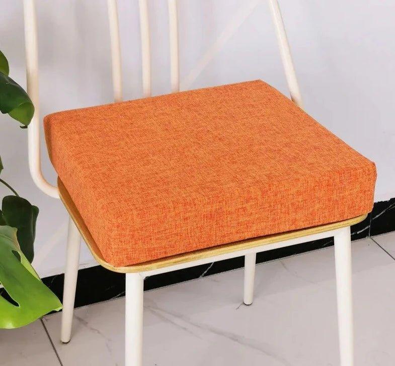 Coussin carré épais orange posé sur une chaise à structure blanche