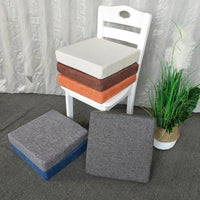 Coussins carrés épais empilés et disposés autour d'une chaise blanche