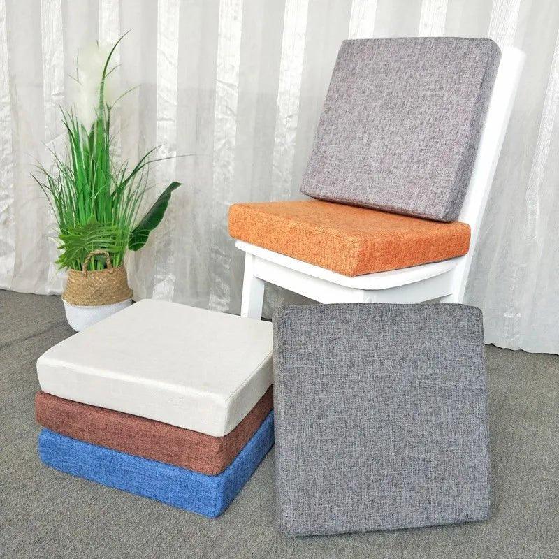 Coussins carrés épais de plusieurs couleurs, avec un modèle orange sur une chaise blanche