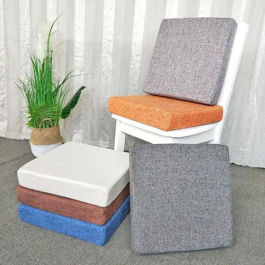 Coussins carrés épais de plusieurs couleurs, avec un modèle orange sur une chaise blanche