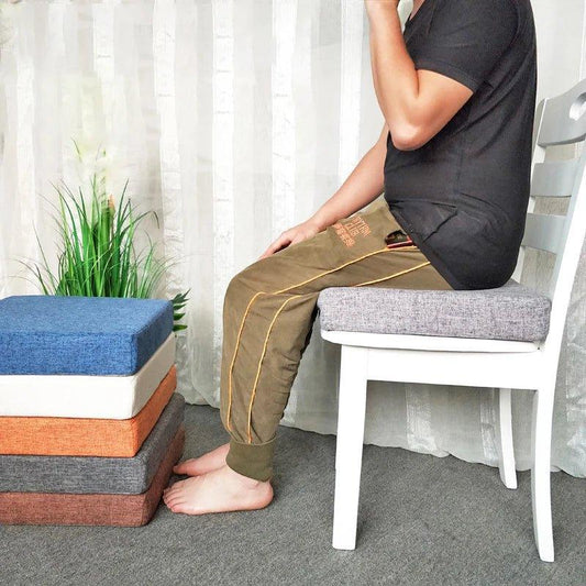 Personne assise sur un coussin carré gris posé sur une chaise blanche