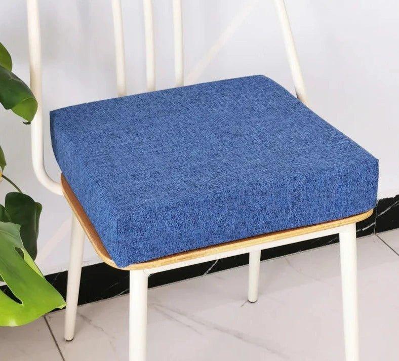 Coussin carré épais bleu posé sur une chaise à structure blanche