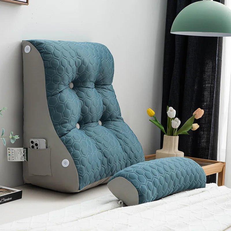 Dossier incliné matelassé bleu-vert avec poche latérale et coussin cylindrique posé sur un lit