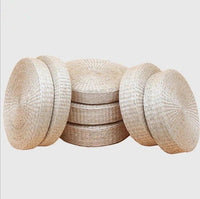 Plusieurs coussins de sol ronds à surface tressée présentés empilés