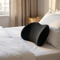 Coussin lombaire de nuit noir posé sur un lit au linge blanc — mise en situation illustrative