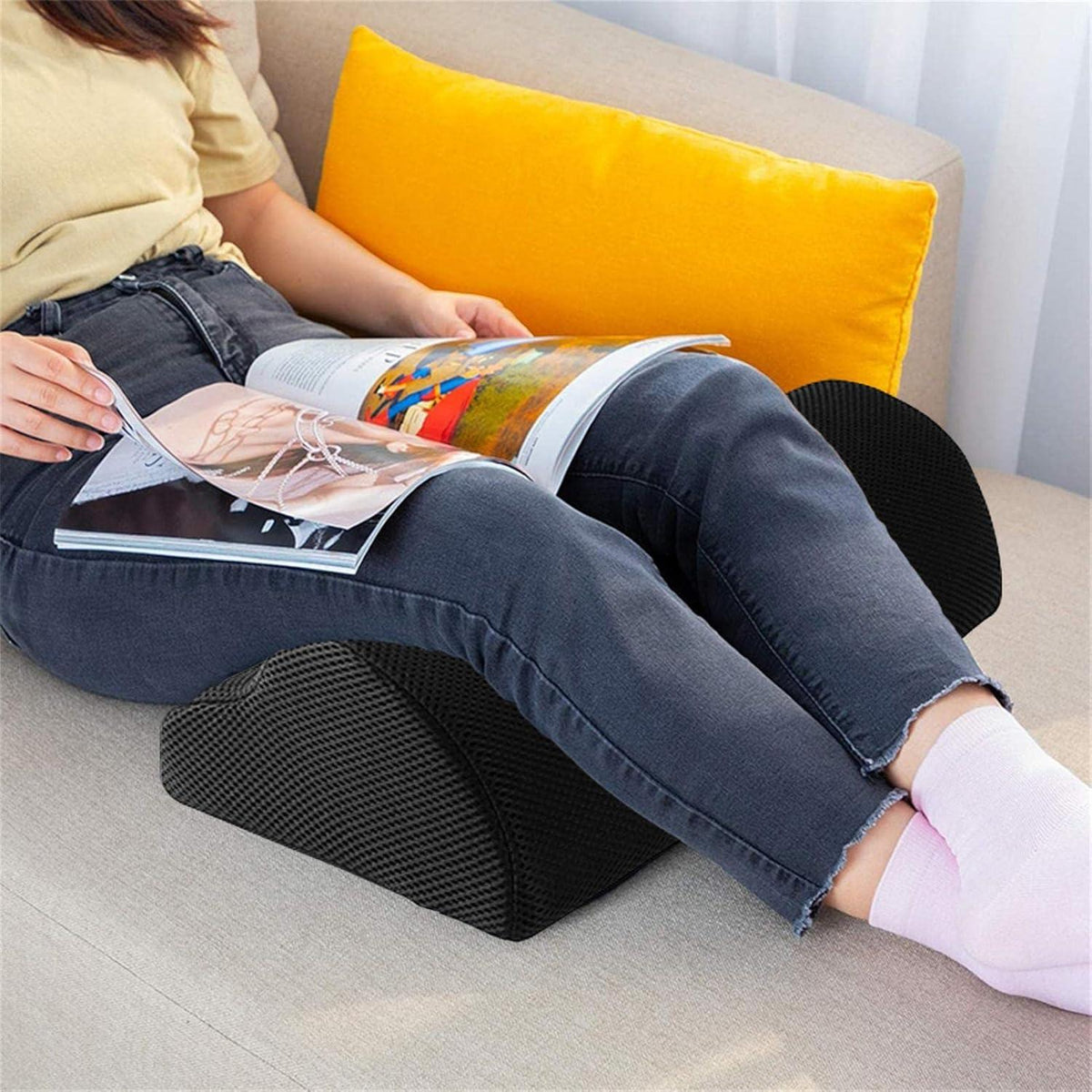 Personne assise sur un canapé avec un coussin noir placé sous les jambes