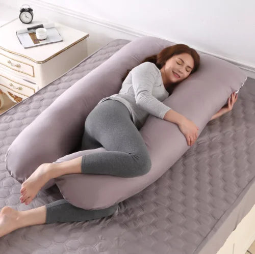 Coussin gris en U présenté en position latérale sur un lit