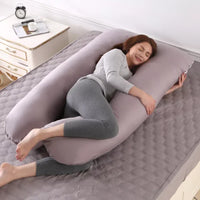 Coussin gris en U présenté en position latérale sur un lit