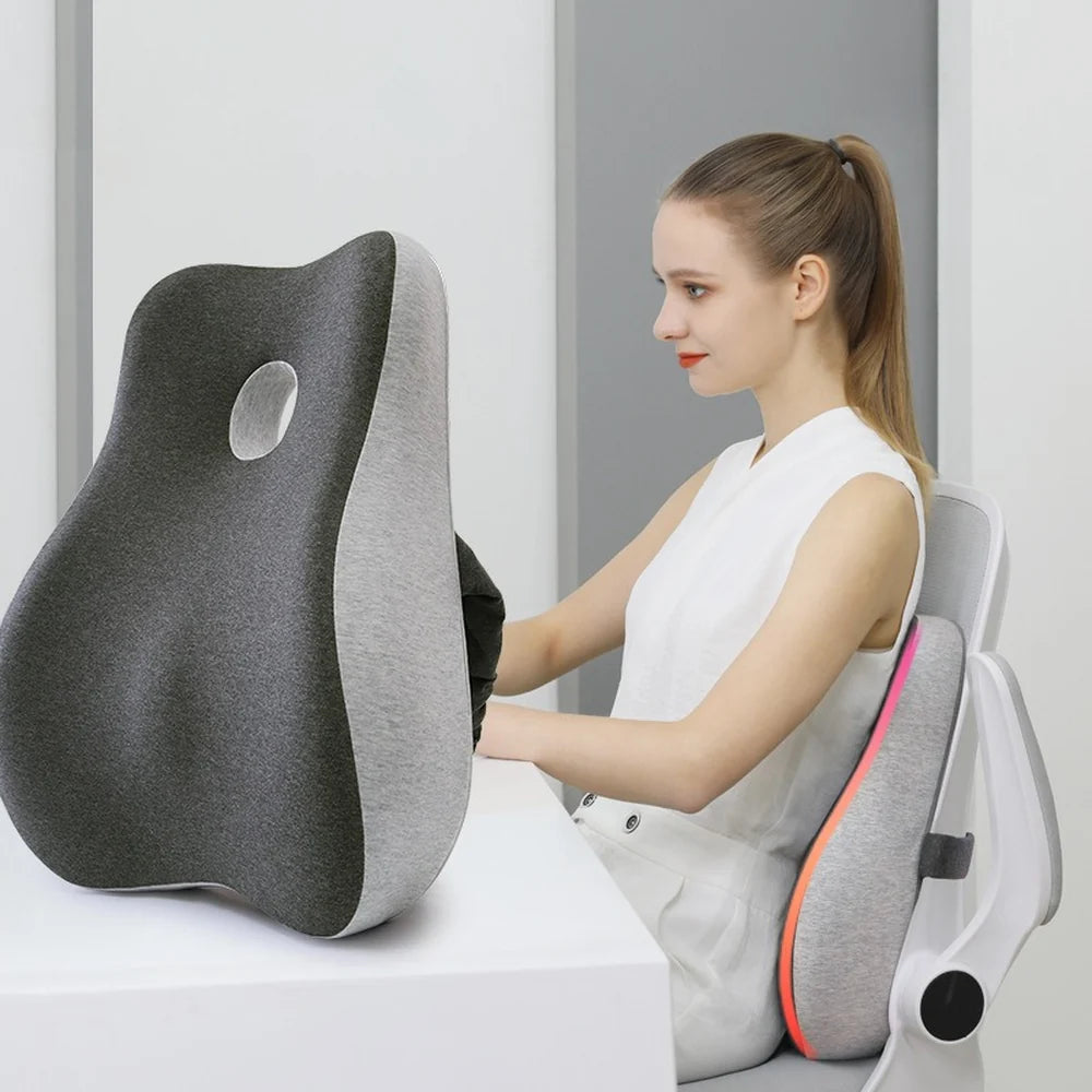 Coussin lombaire gris ErgoCore contre le dossier d’une chaise de bureau, utilisatrice assise au bureau