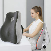 Coussin lombaire gris ErgoCore contre le dossier d’une chaise de bureau, utilisatrice assise au bureau