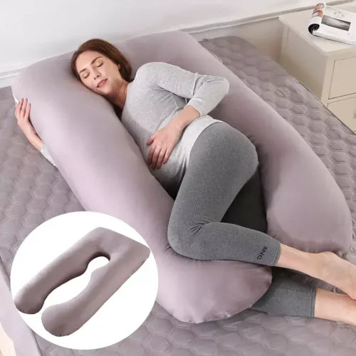 Coussin de grossesse gris en forme de U présenté sur un lit