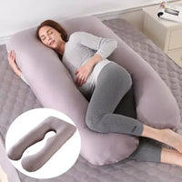 Coussin de grossesse gris en forme de U présenté sur un lit