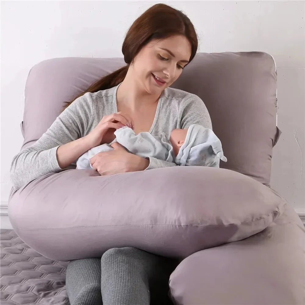 Maman assise dans le coussin en U NidDouillet pendant l’allaitement de son bébé